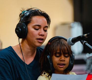 A young woman and child singing into a microphone