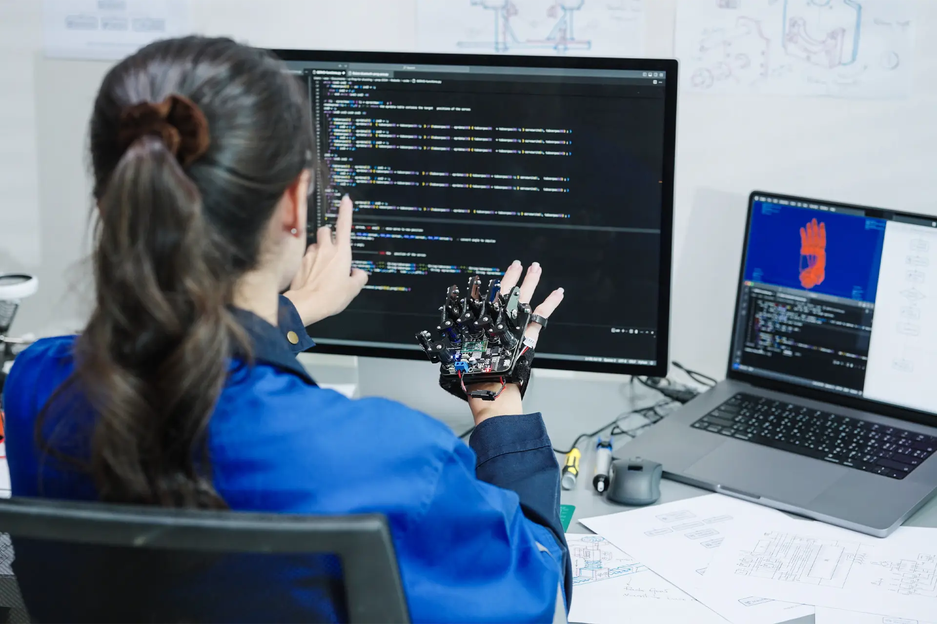 Woman with robotic glove looks at computer screen