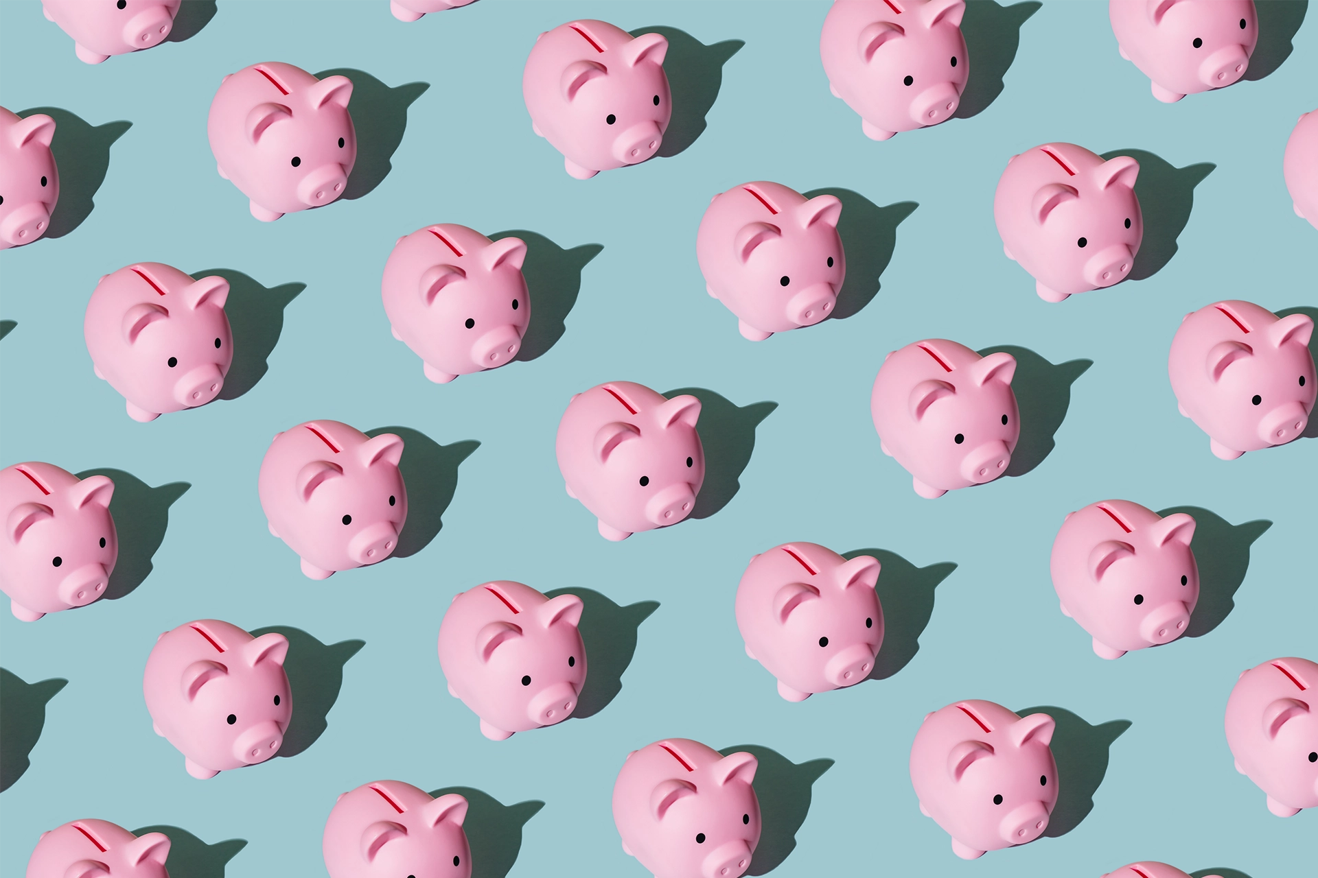 Small pink piggy banks lined up in a pattern on light blue background