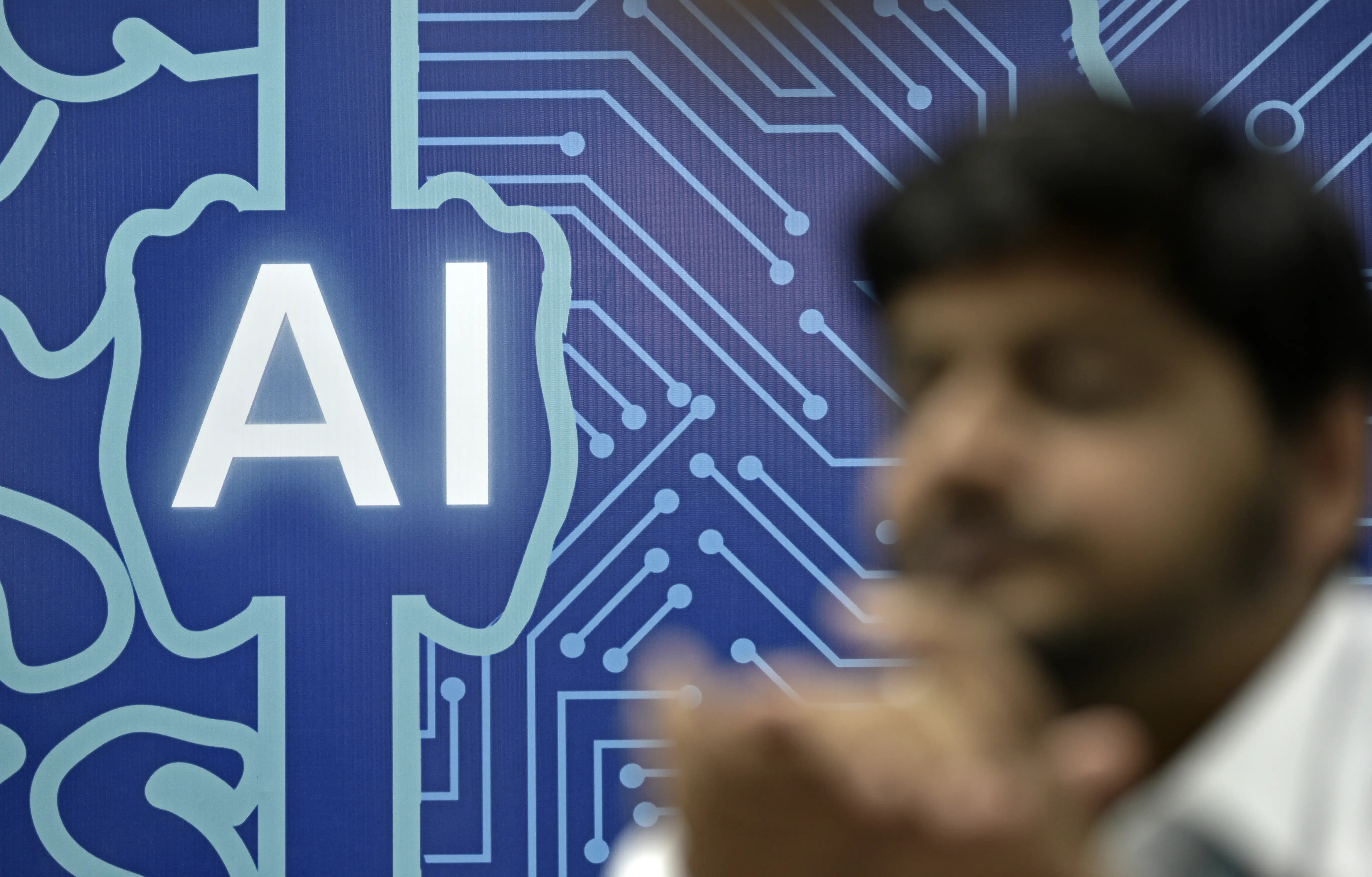 A sign with AI and a brain with a man sat in front of it.