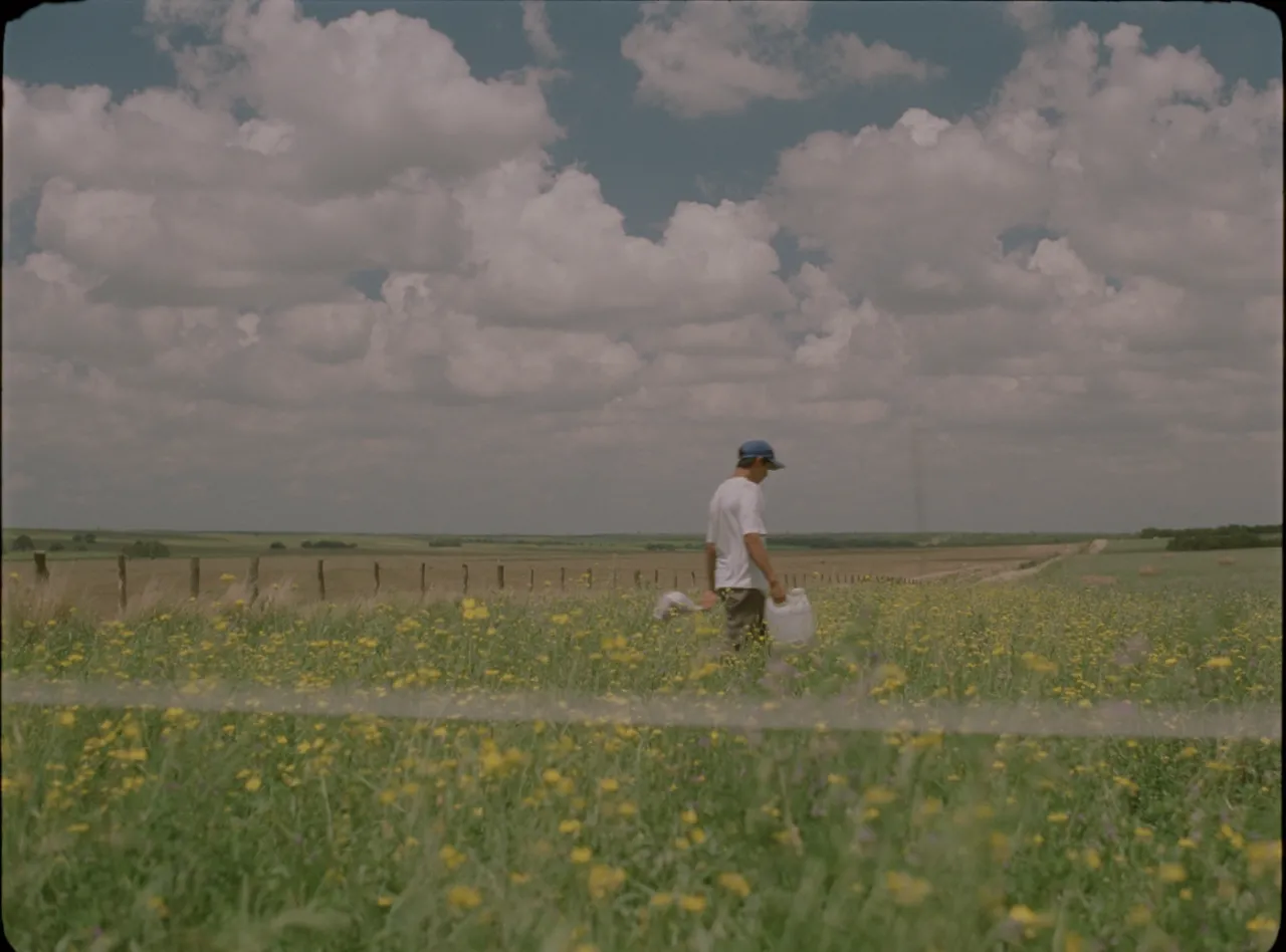 A film still of a man walking in a field