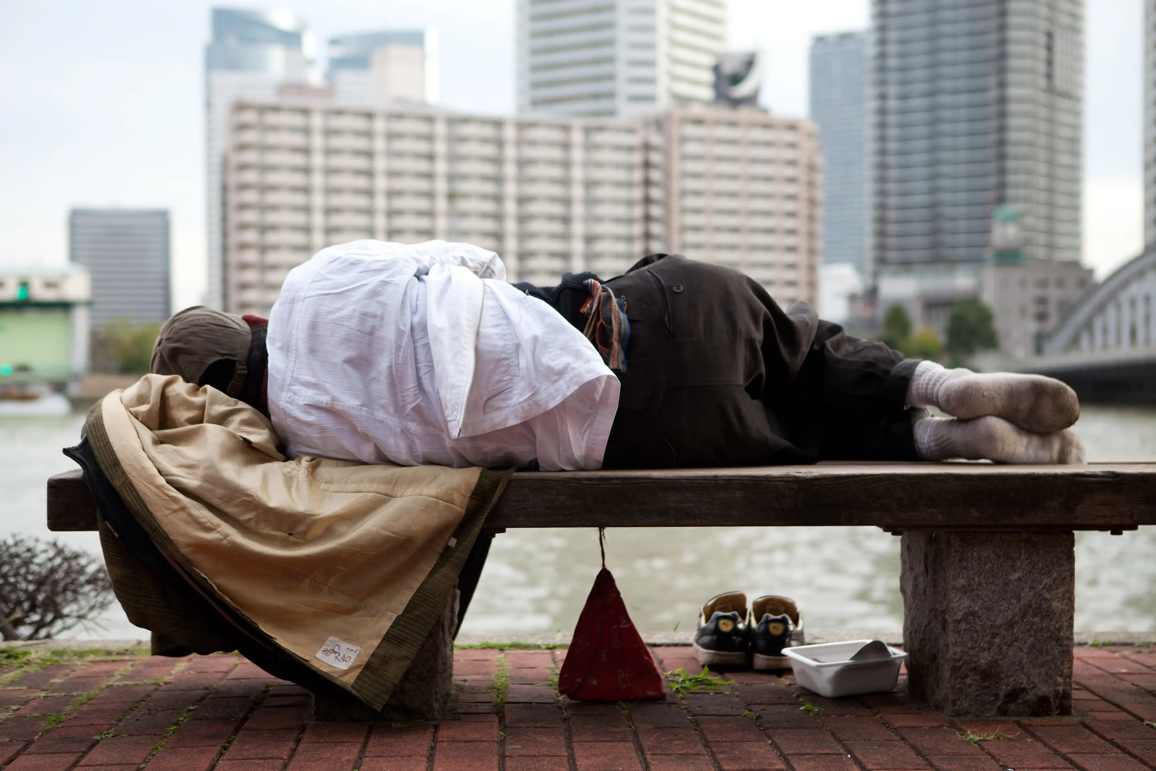 A person sleeping on a bench in a city in Japan