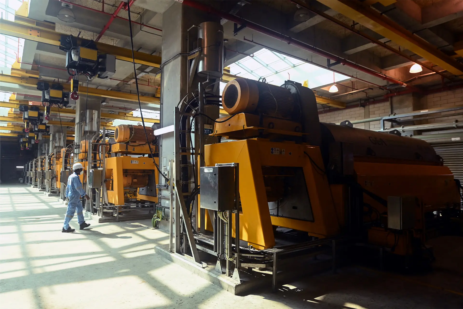 A man examines a series of machines in a large shed