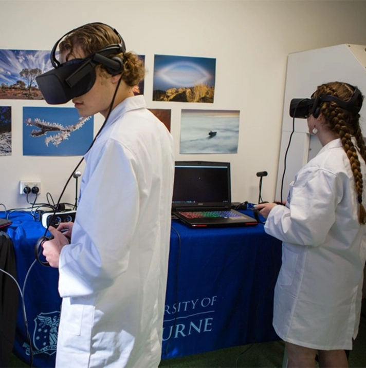 Two university students in lab coats wearing VR headsets