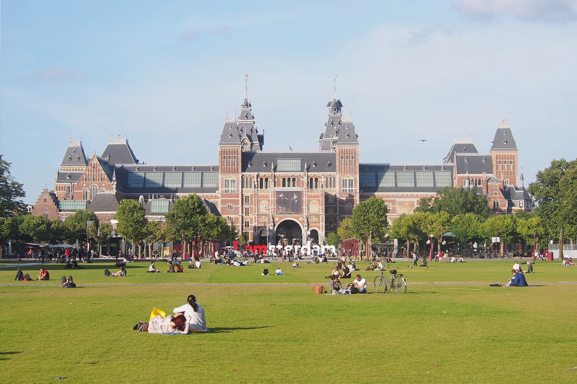 A palatial building with people relaxing in a park in front