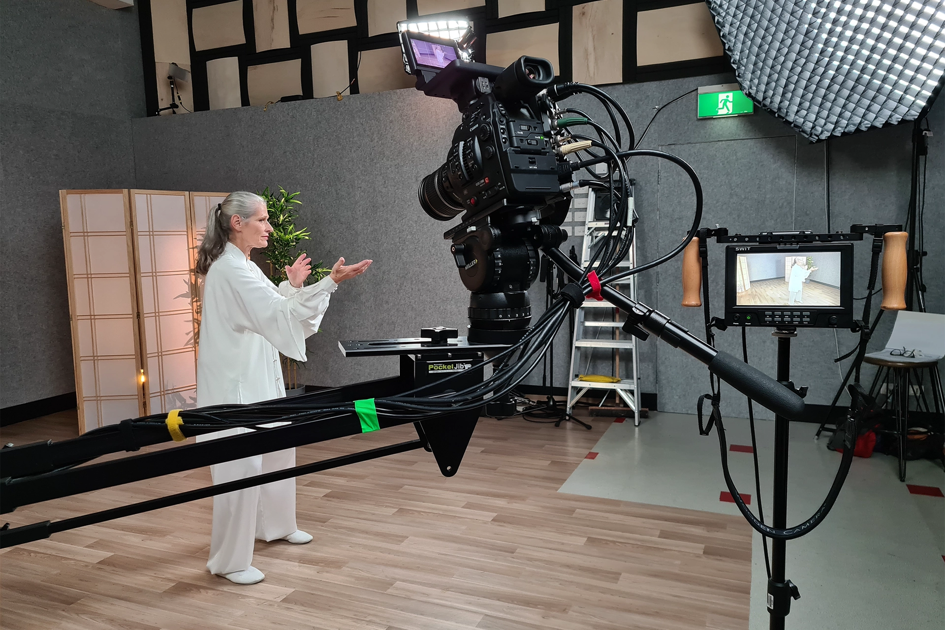 A woman demonstrating Tai Chi in front of a large video camera