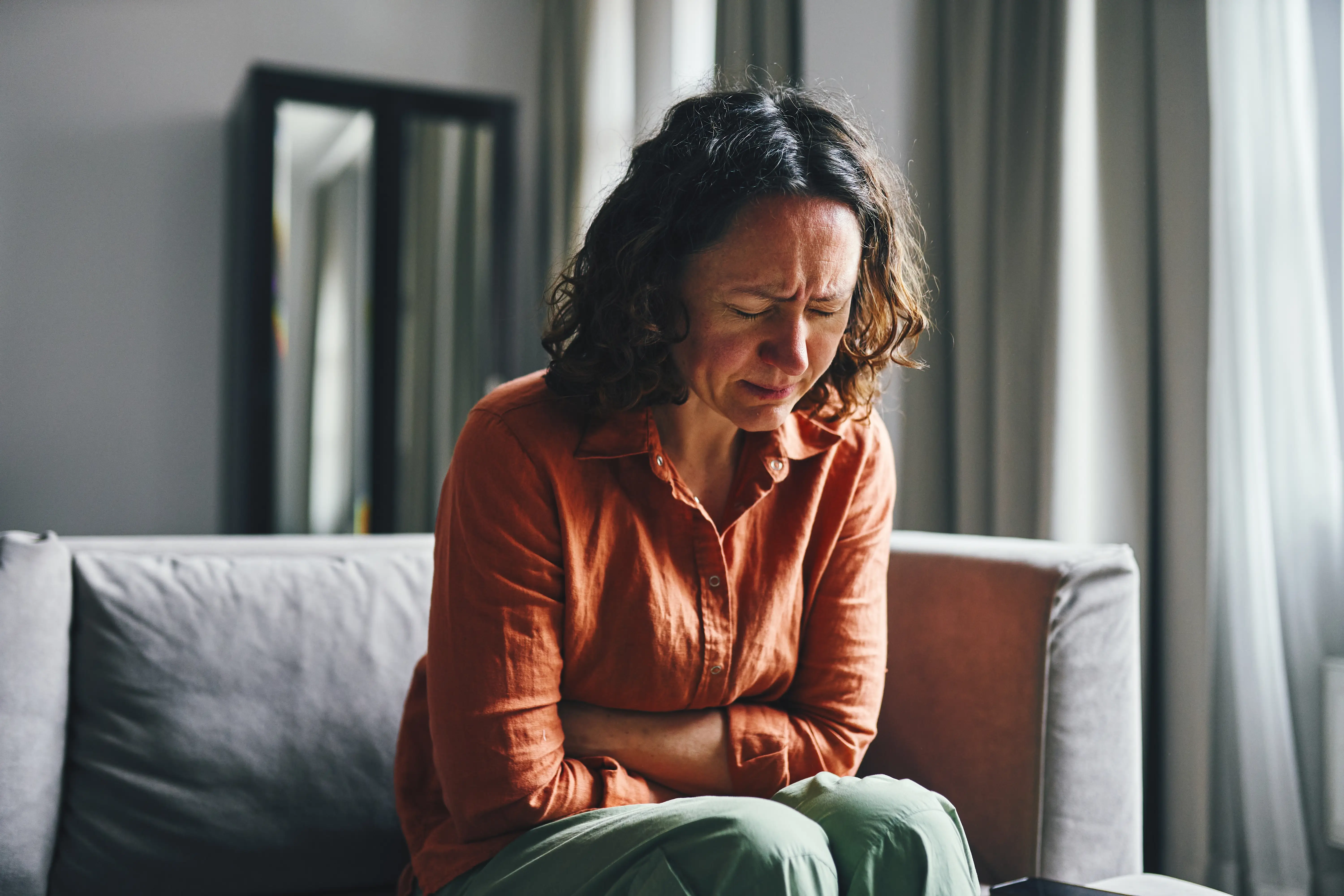 A woman leans over in pain clutching her stomach