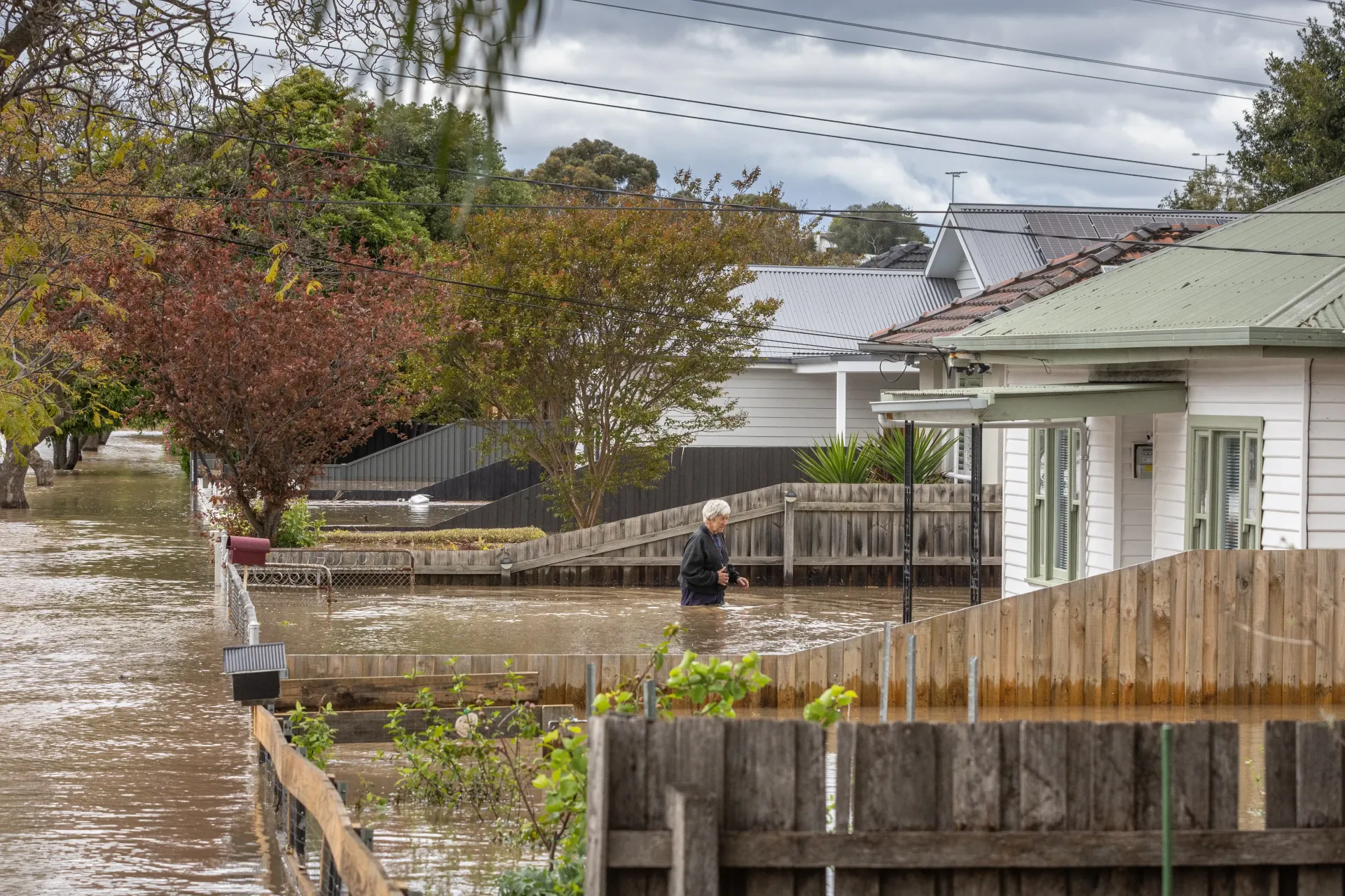 Woman walks through flooded front yard
