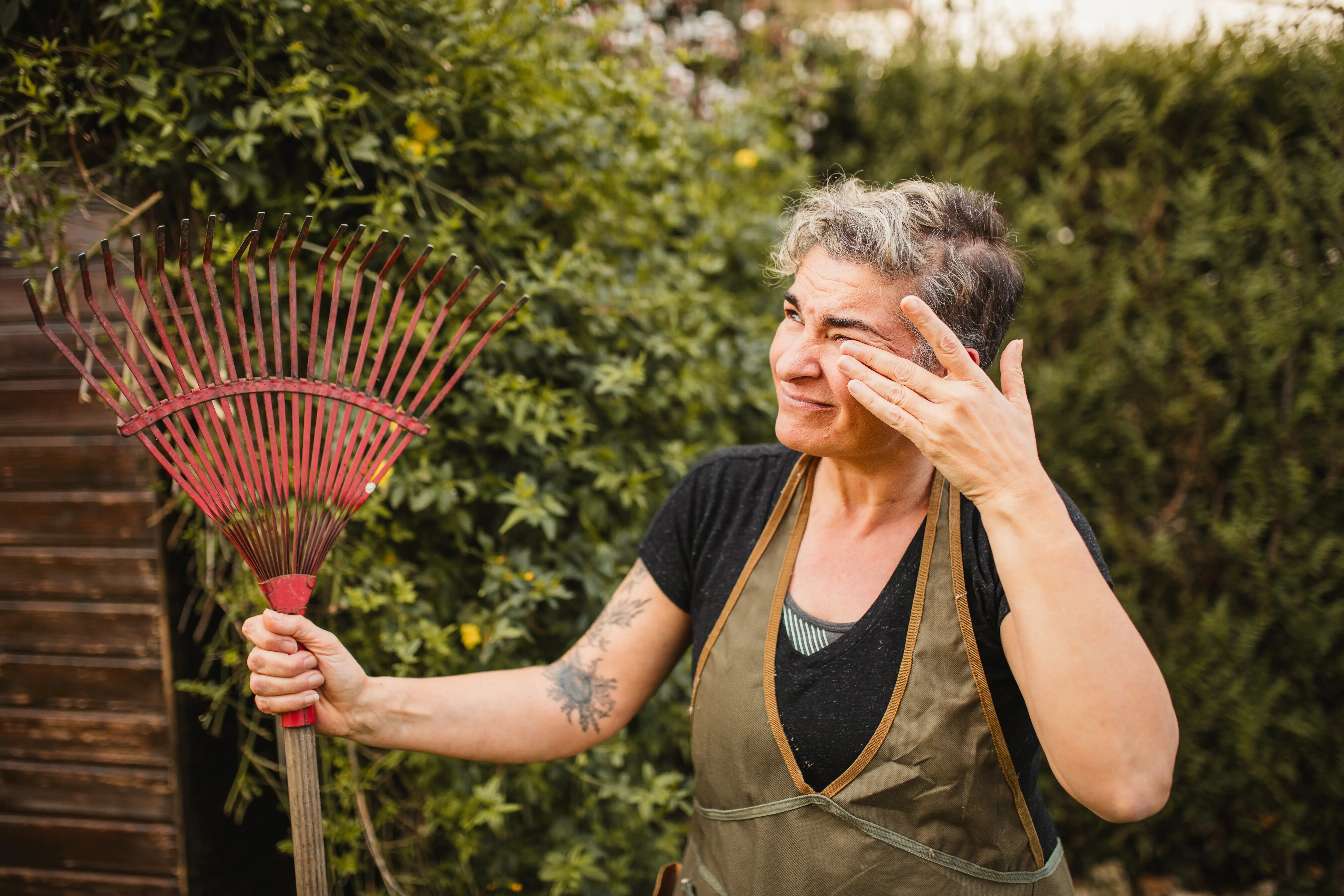 A woman rubbing her itchy eyes as she works in the garden