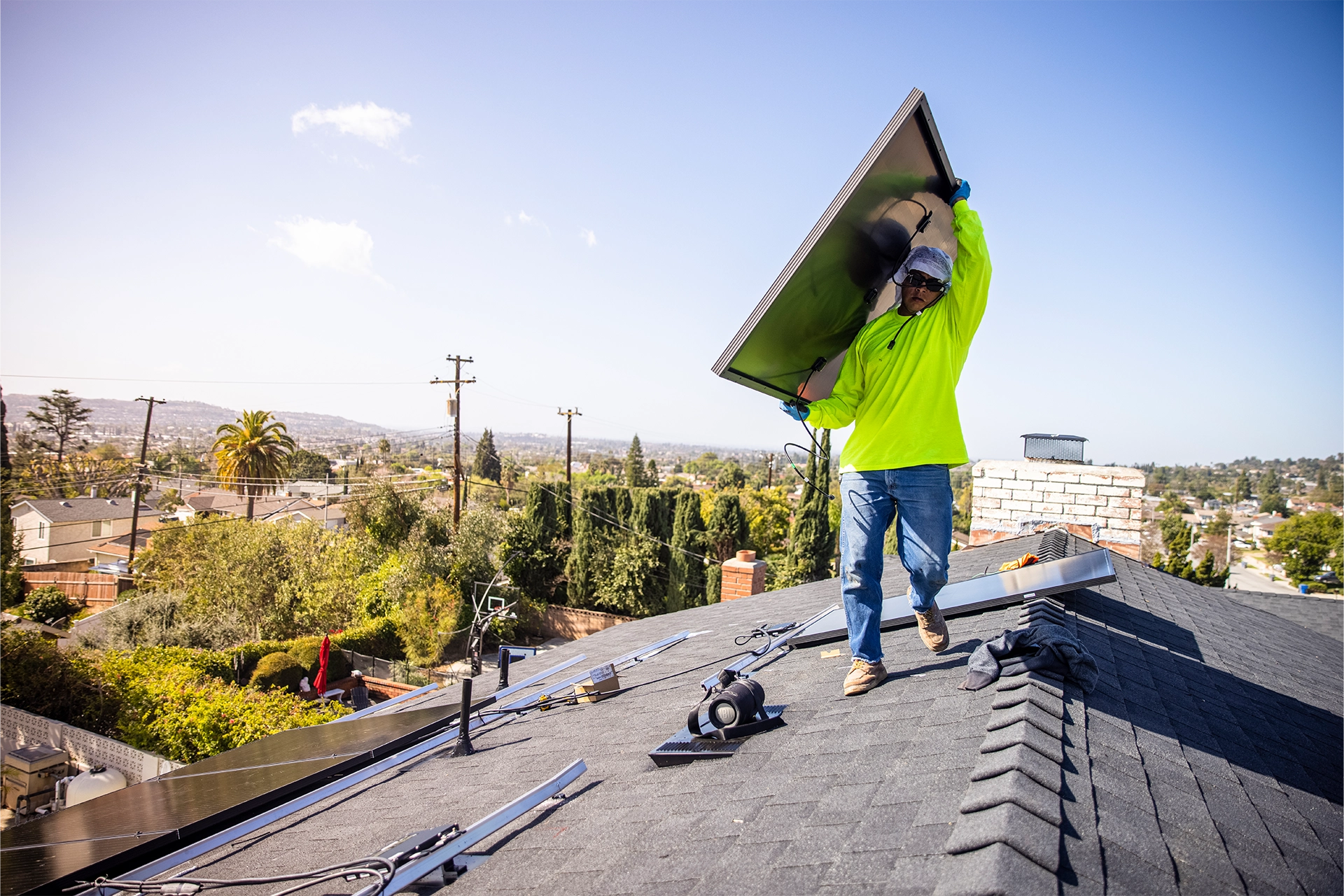 Man in hi-vis jumper installing solar panel on roof of a California building