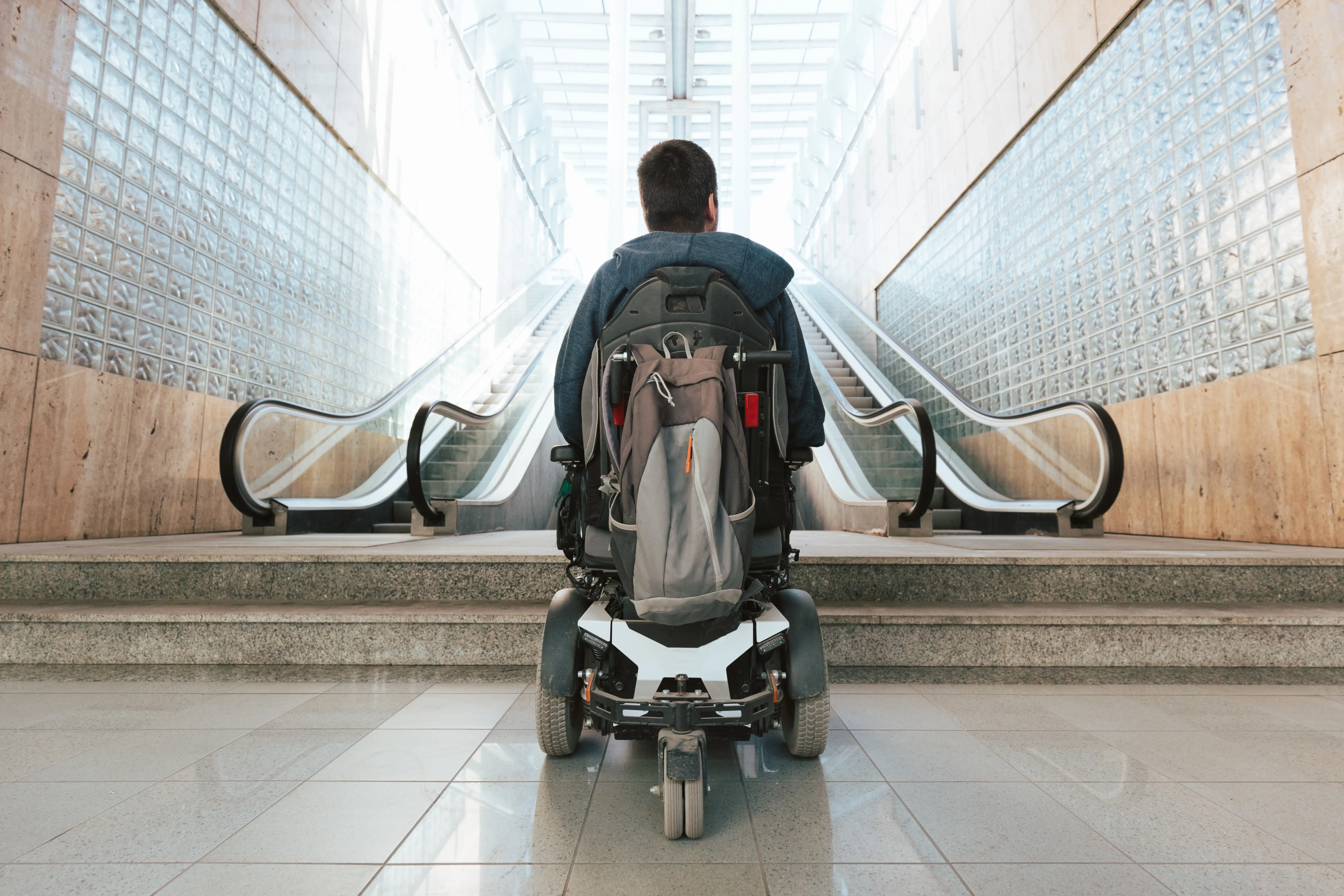 Man with disability on wheelchair stopped in front of staircase, raising awareness of architectural barriers and accessibility issues
