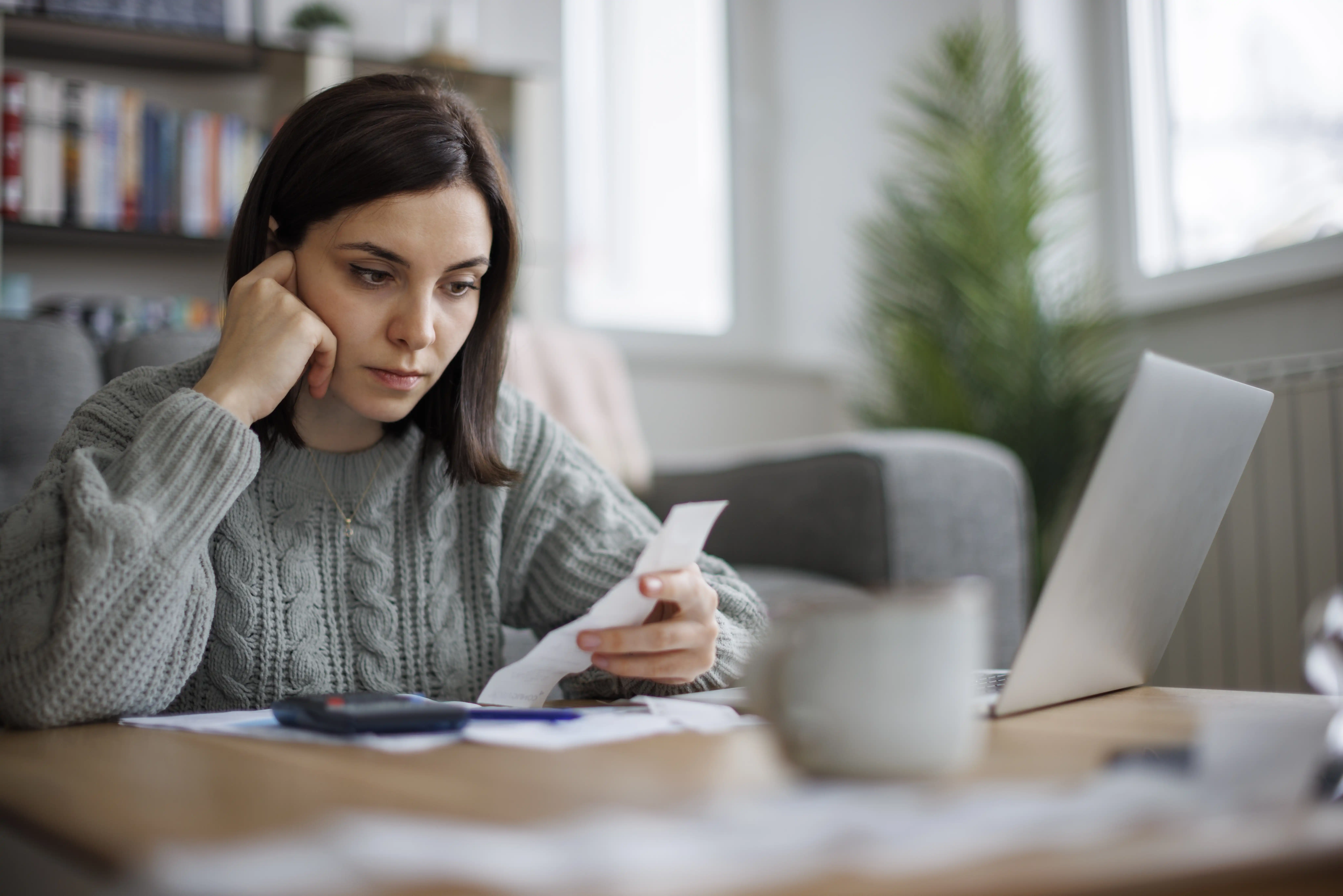 A concerned woman reviews a receipt while sitting at her desk