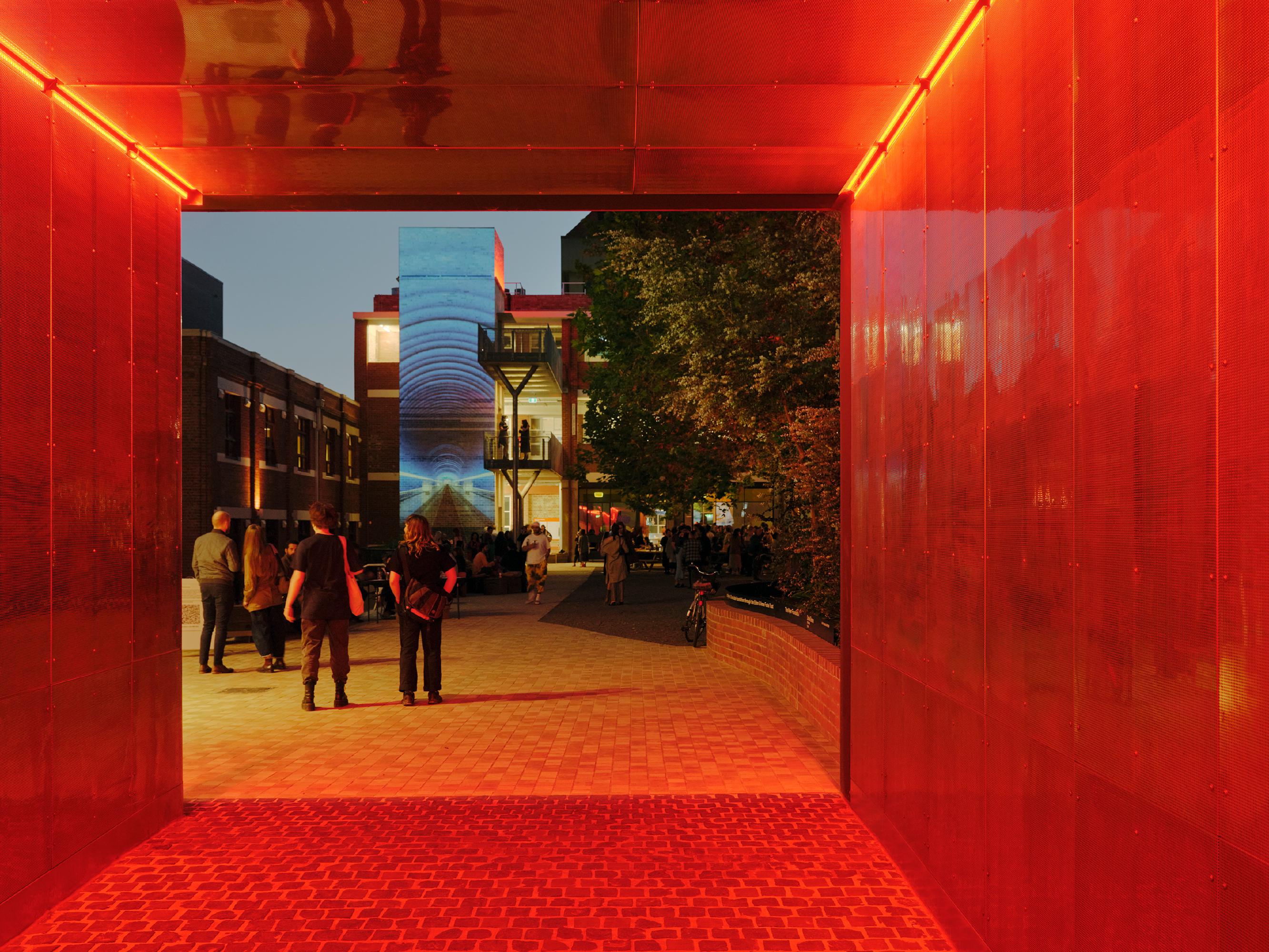 A glowing red walkway opening into an open courtyard at Collingwood Yards