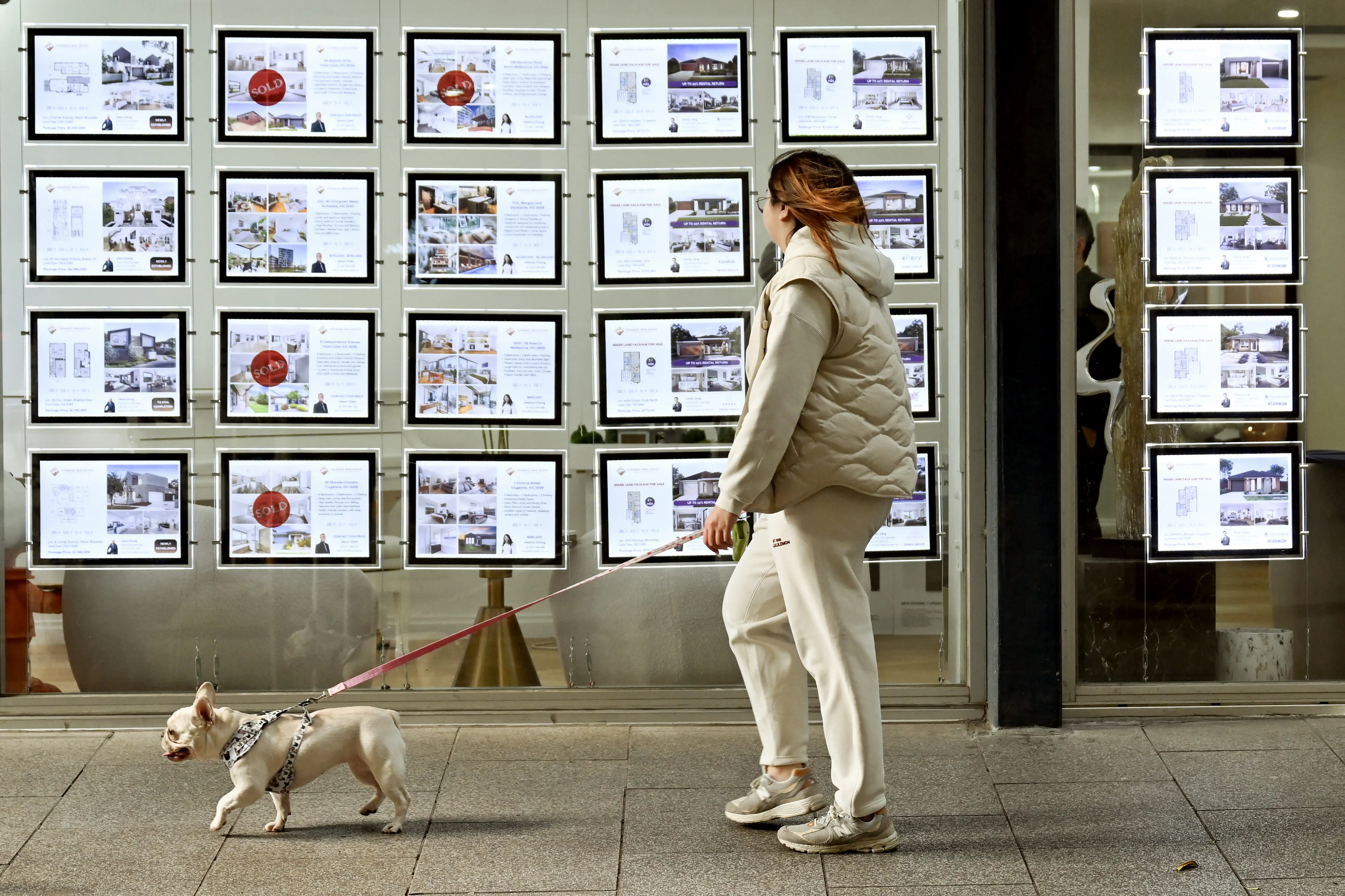 A pedestrian walks past a real estate agency