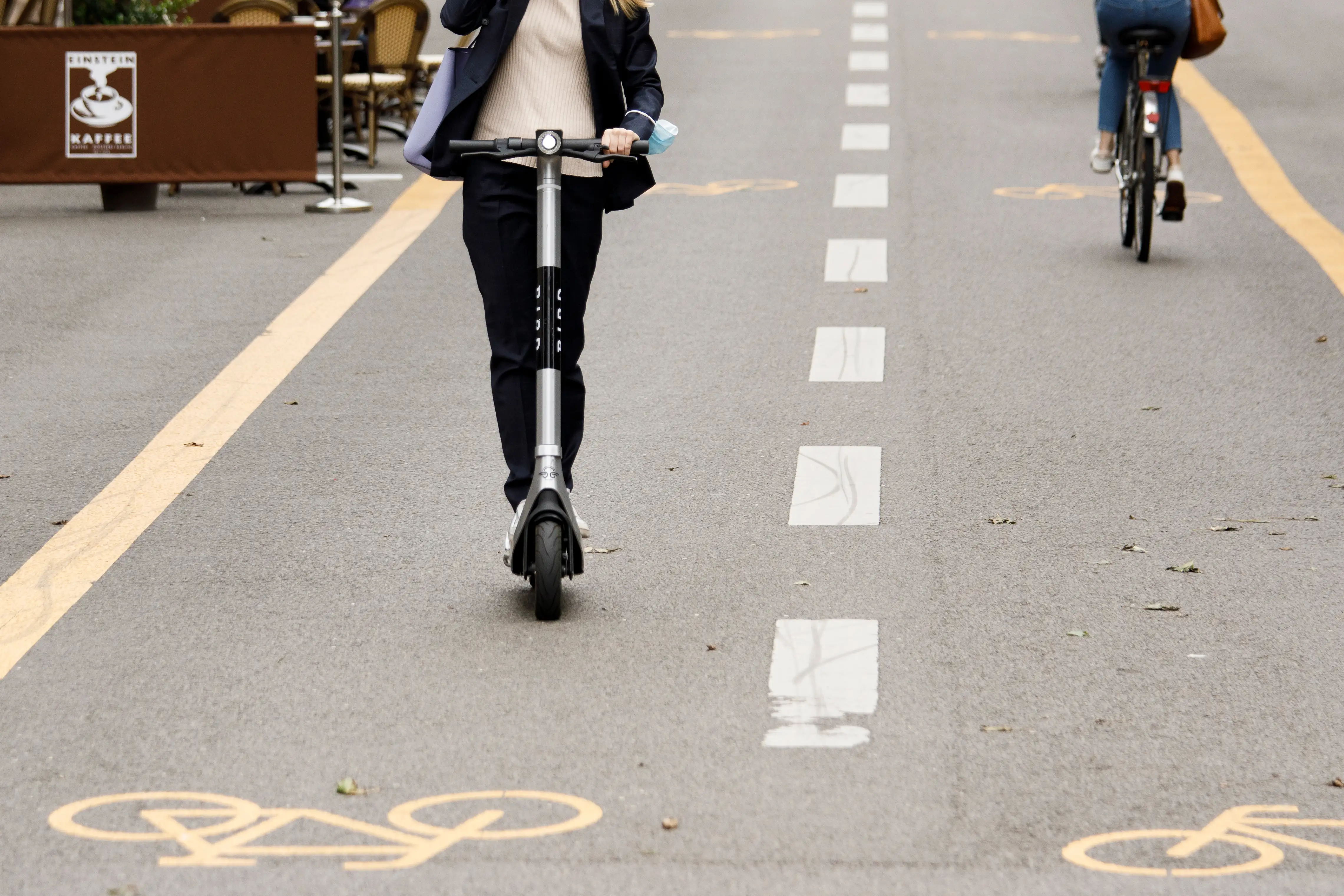 A young person rides on an e-scooter in a designated bike lane.