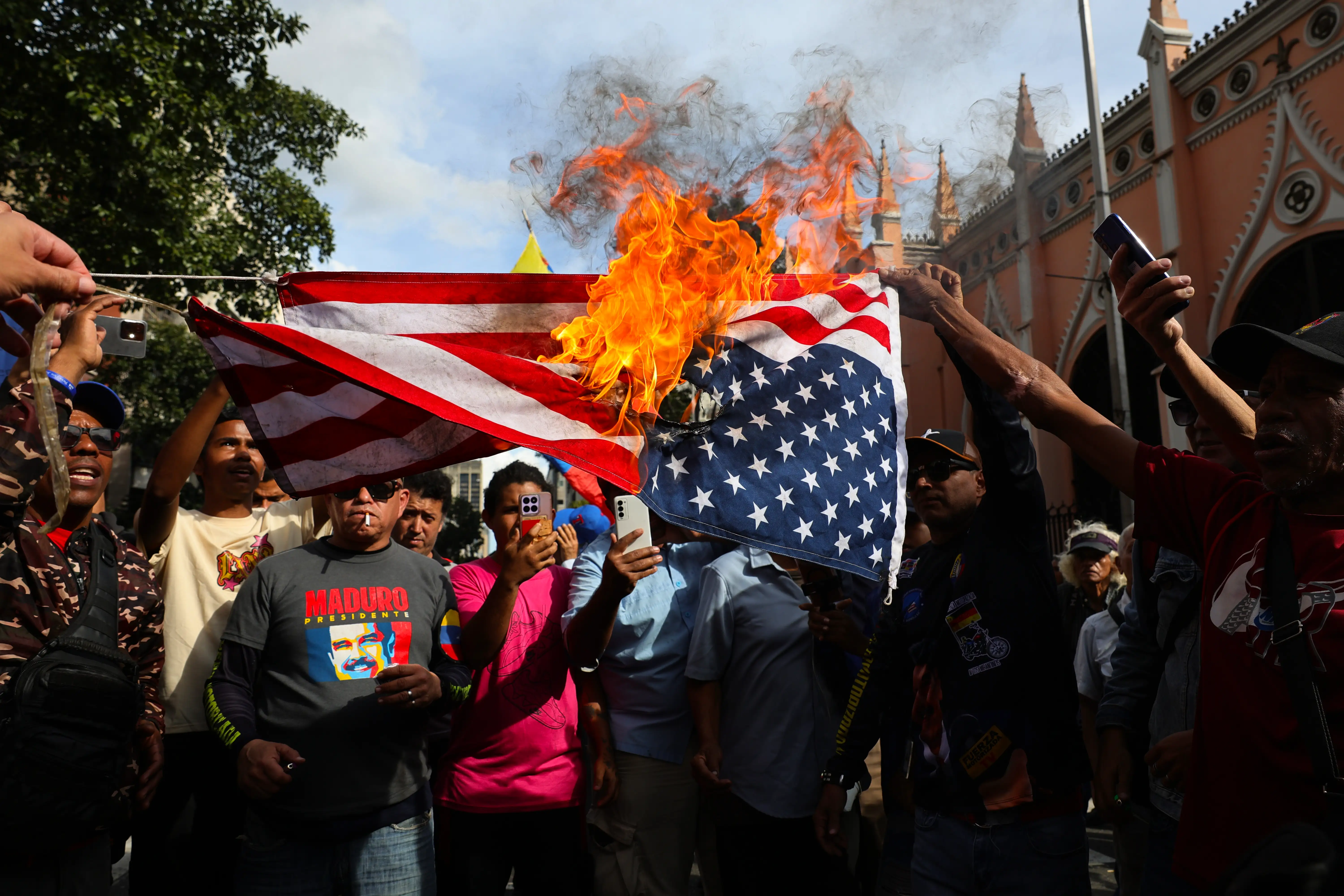 Supporters of Nicolas Maduro burn a United States flag during near Miraflores palace in Venezuela.