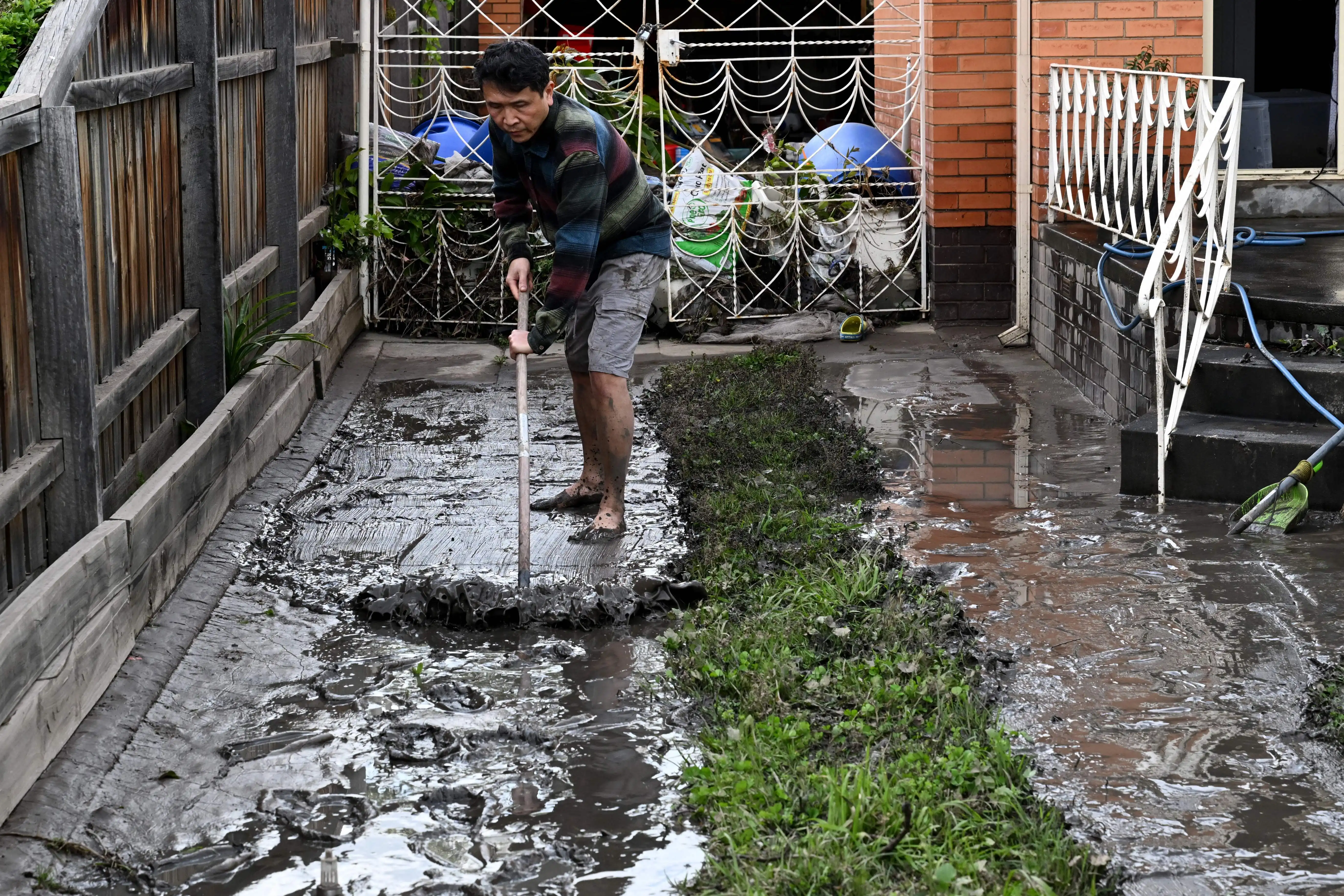 A man clears mud from his driveway which has been affected by floods