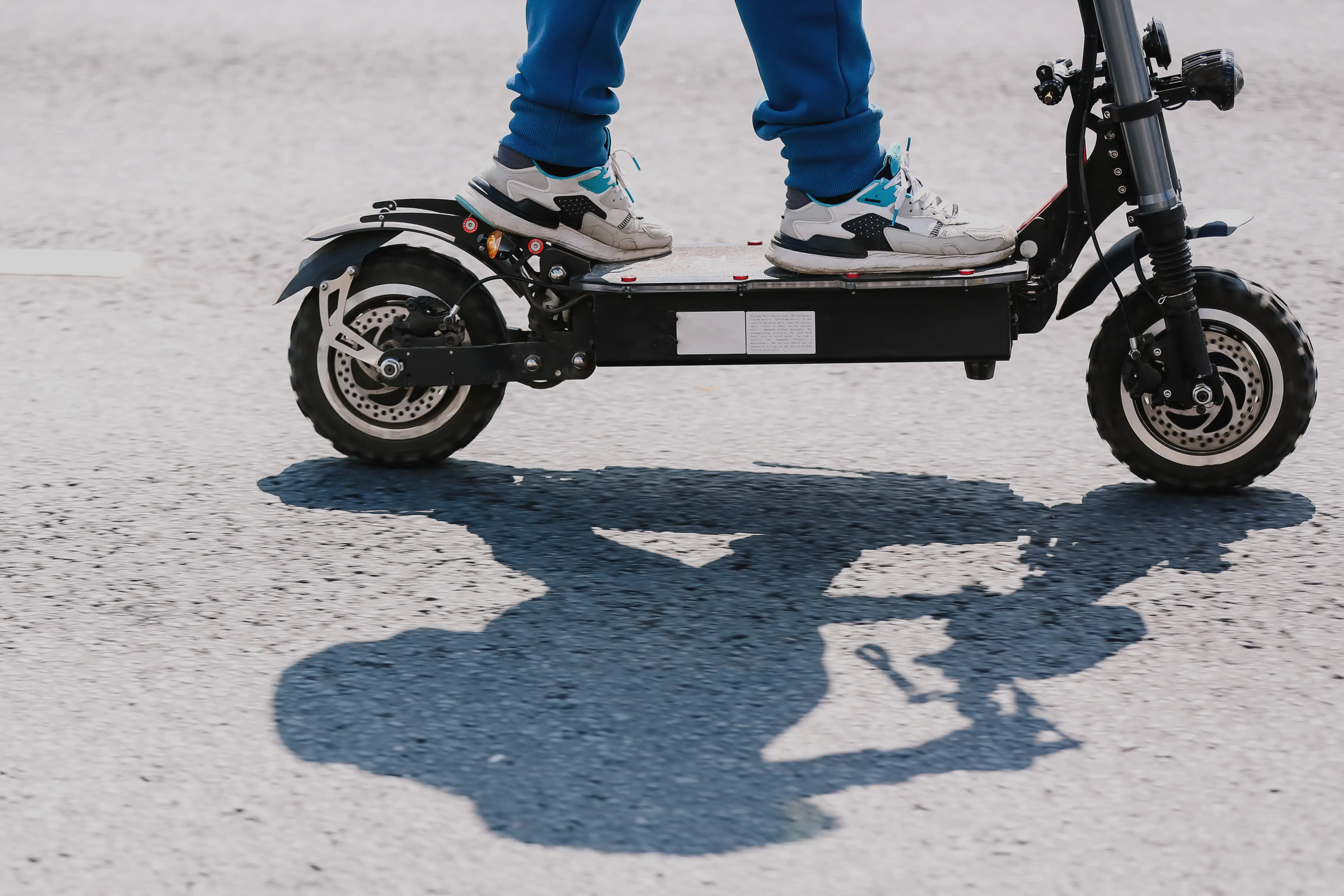 A close-up of sneakers on an e-scooter.