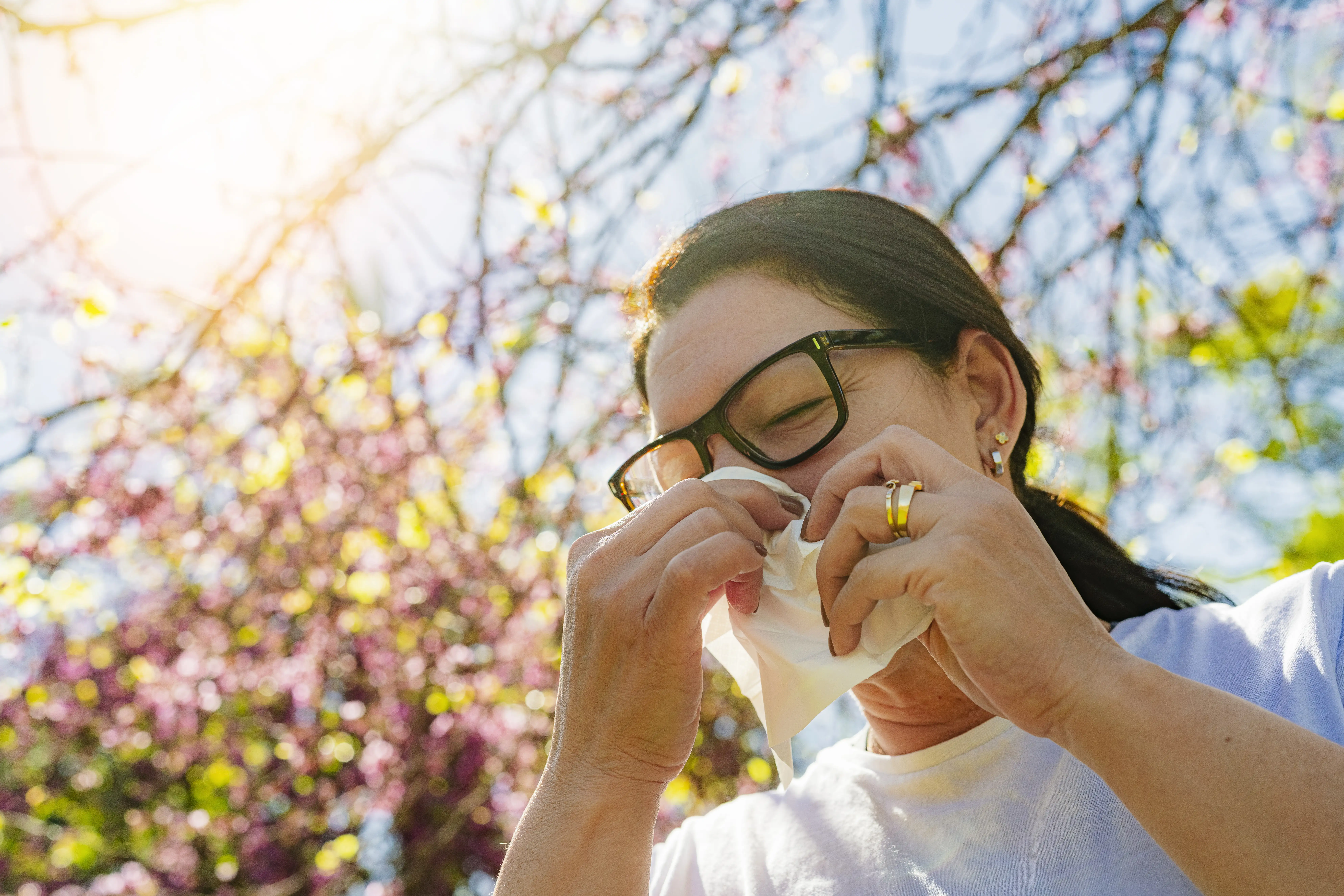 A woman outside holding a tissue to her nose