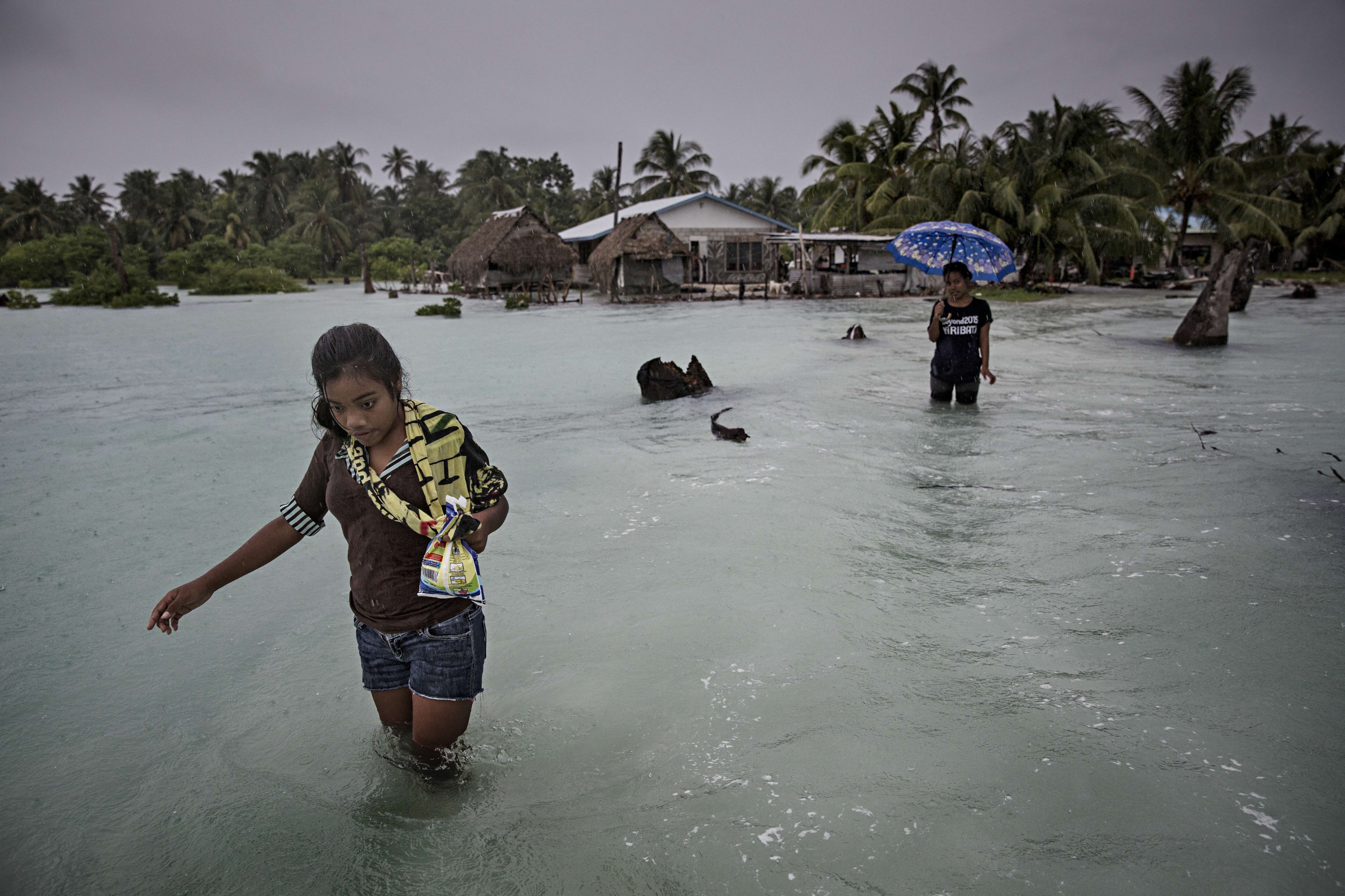 Young woman wades through floods in Kiribati