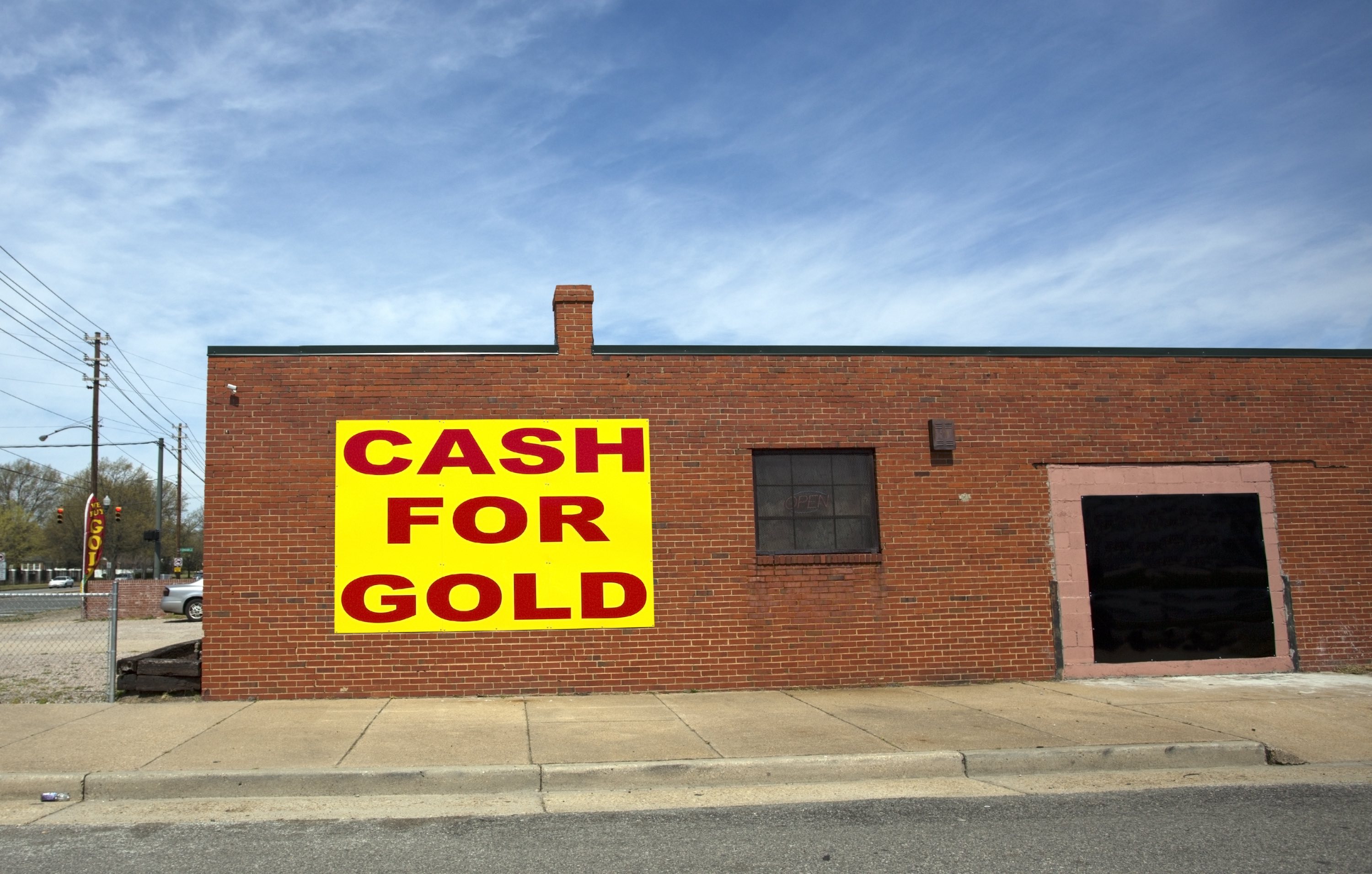 A sideview of a brick pawnbrokers with a sign saying 'cash for gold'