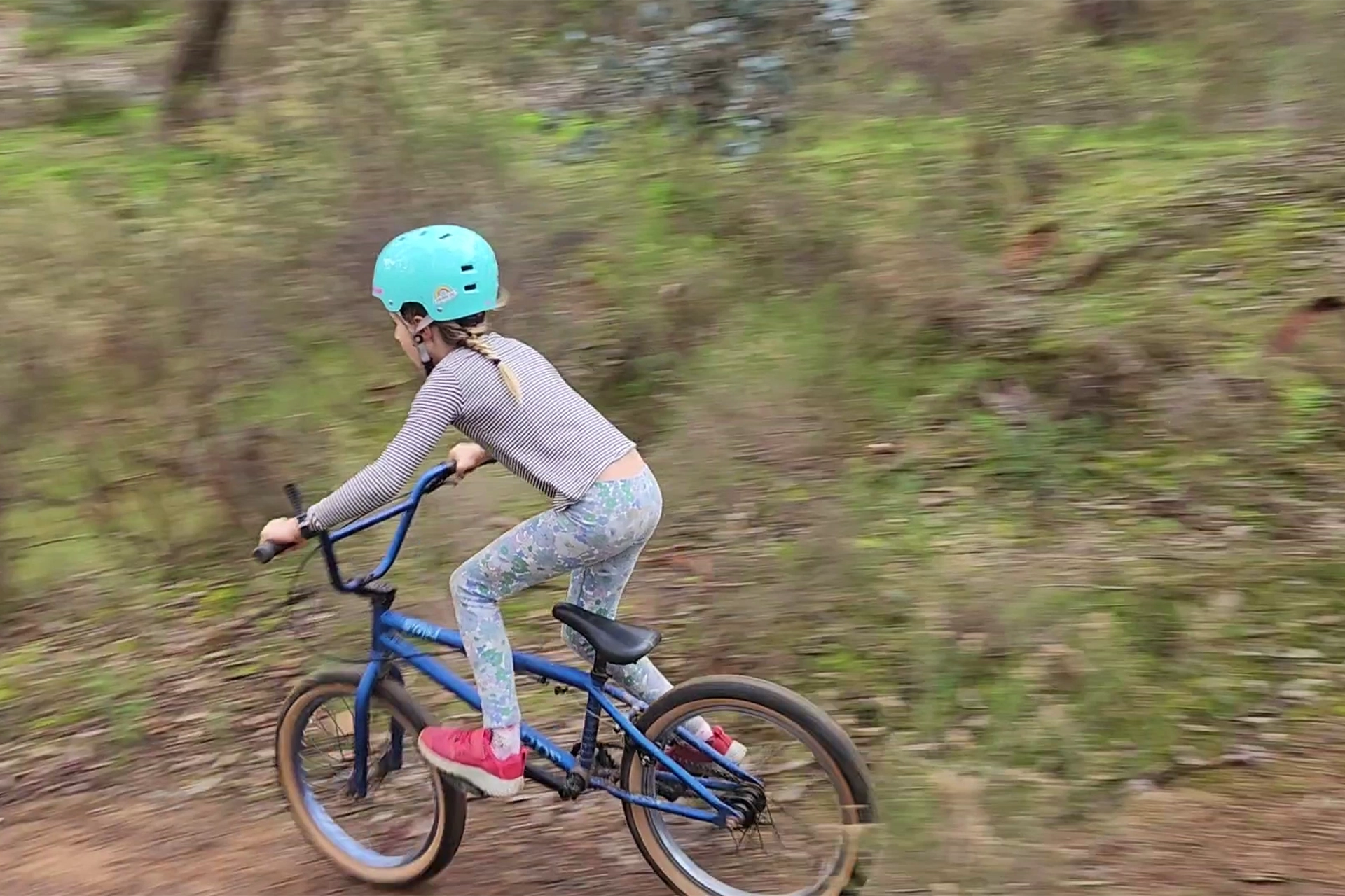 A girl riding a bike down a dirt slope