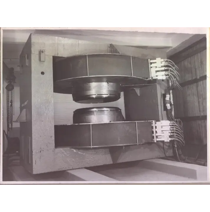 Old photo of a large round machine with two metal drums facing one another