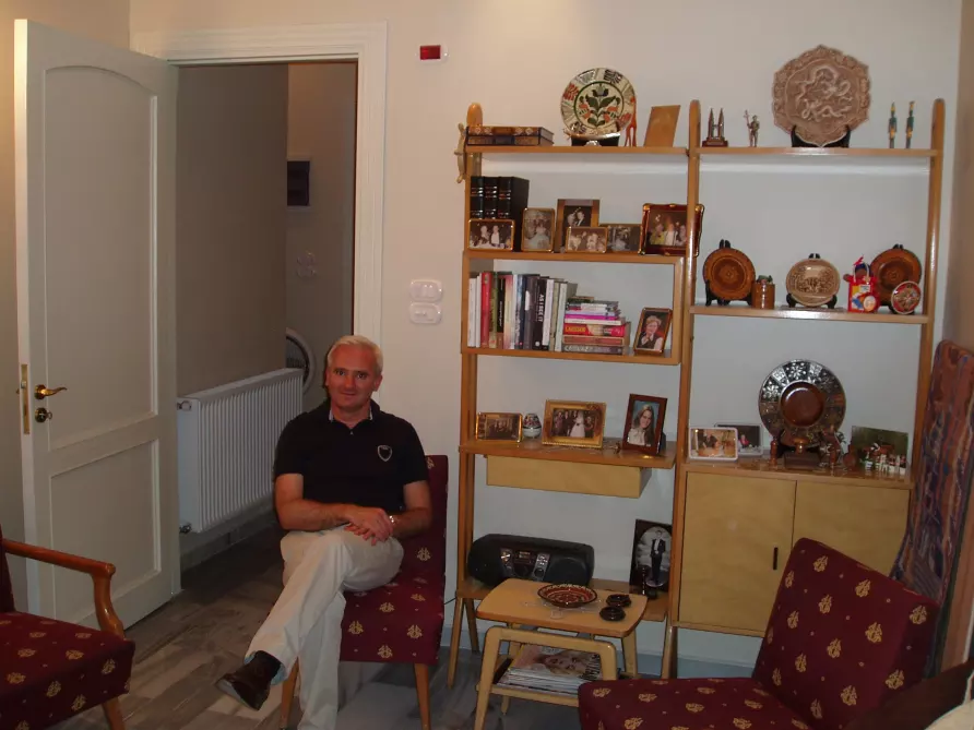 White-haired man sitting in a living room